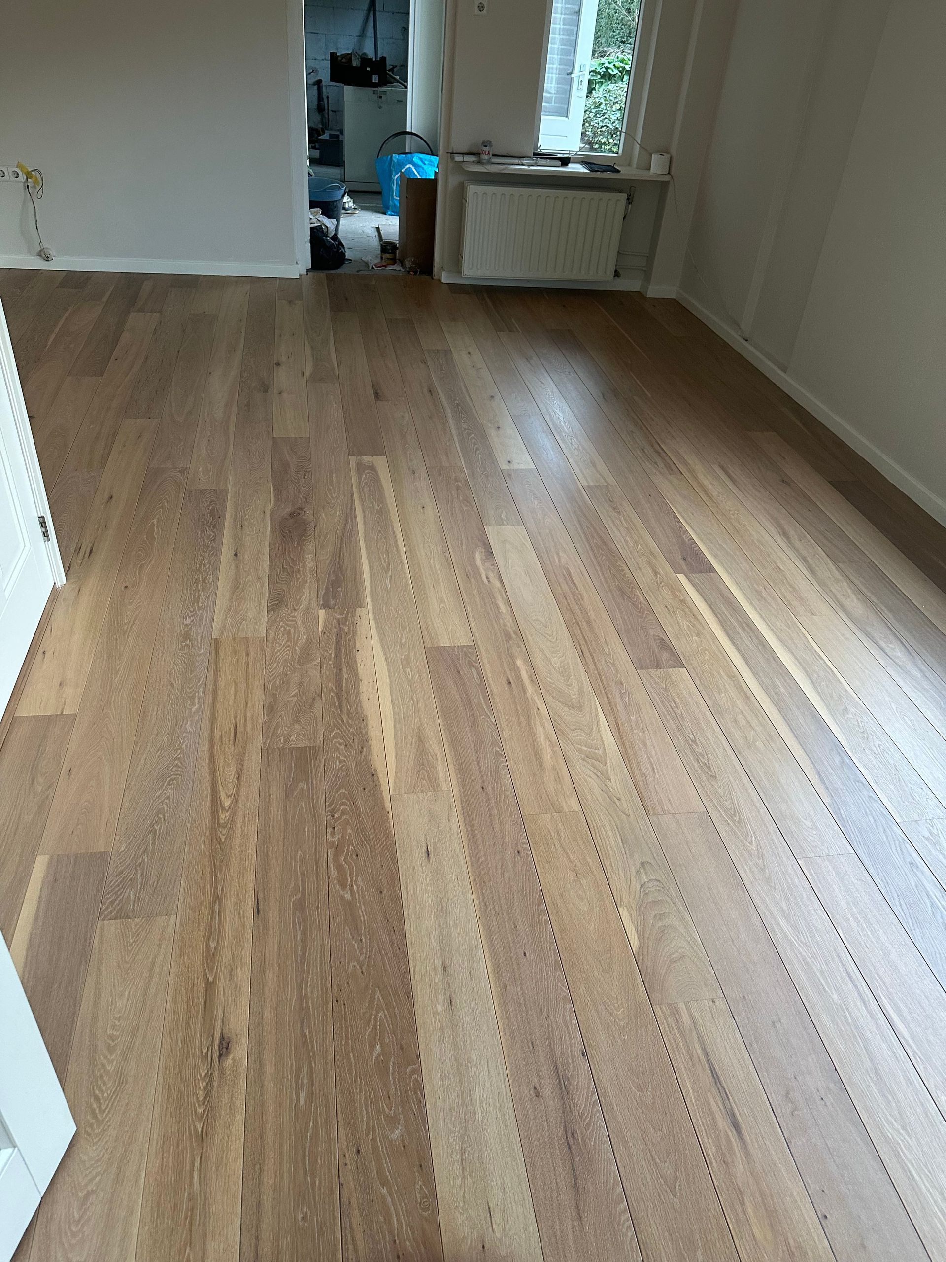 Een kamer met een houten vloer en witte muren.