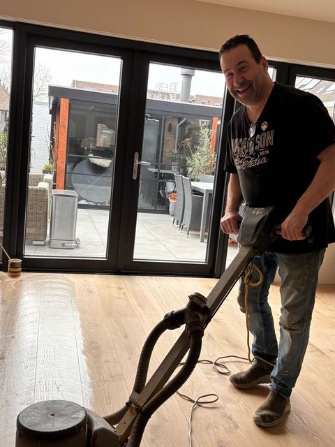Een man gebruikt een machine om een houten vloer te polijsten.