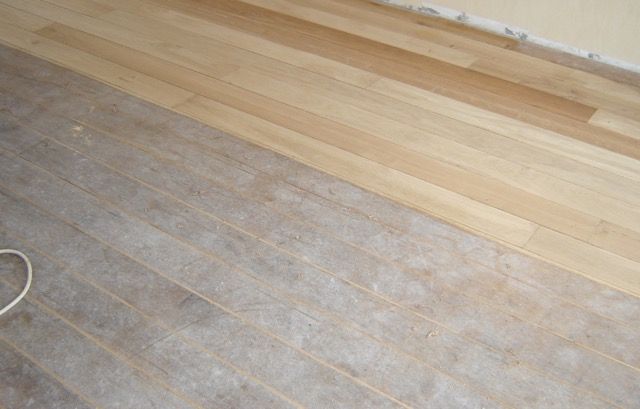 Een houten vloer met een stuk geschuurd opervlakt