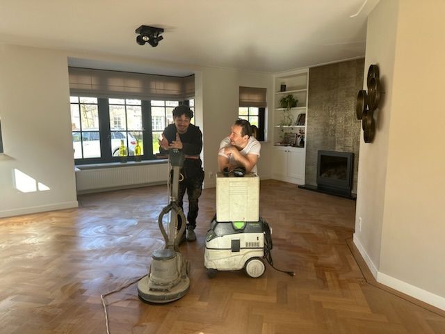 Iemand dweilt een houten vloer met een dweil.