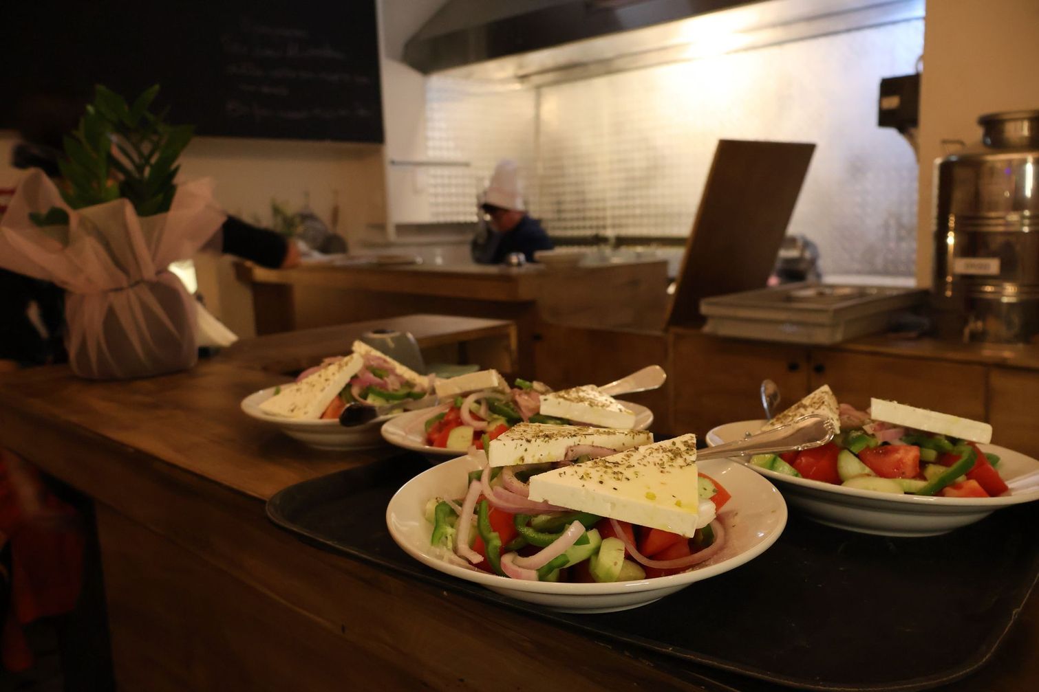 A tray of salads is sitting on a counter in a restaurant.