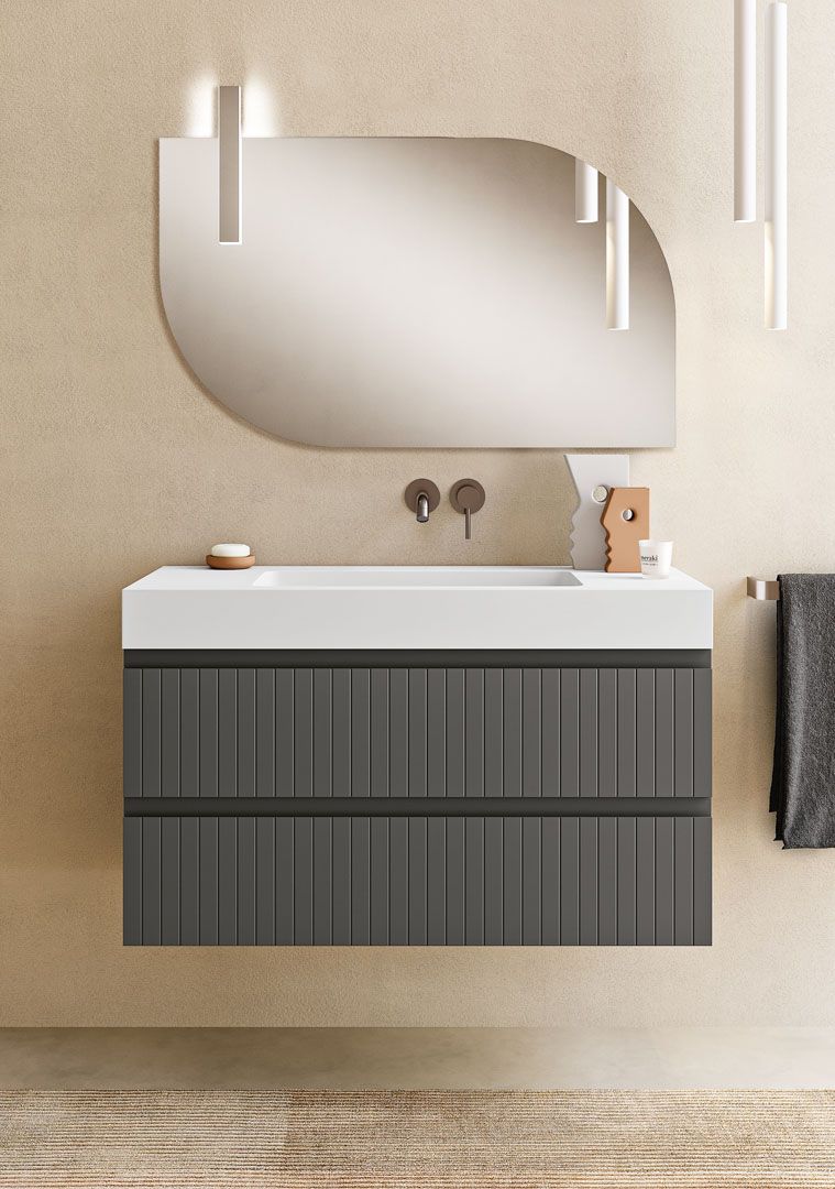 Mobile bagno grigio con piano bianco, specchio rotondo e lampade a sospensione.