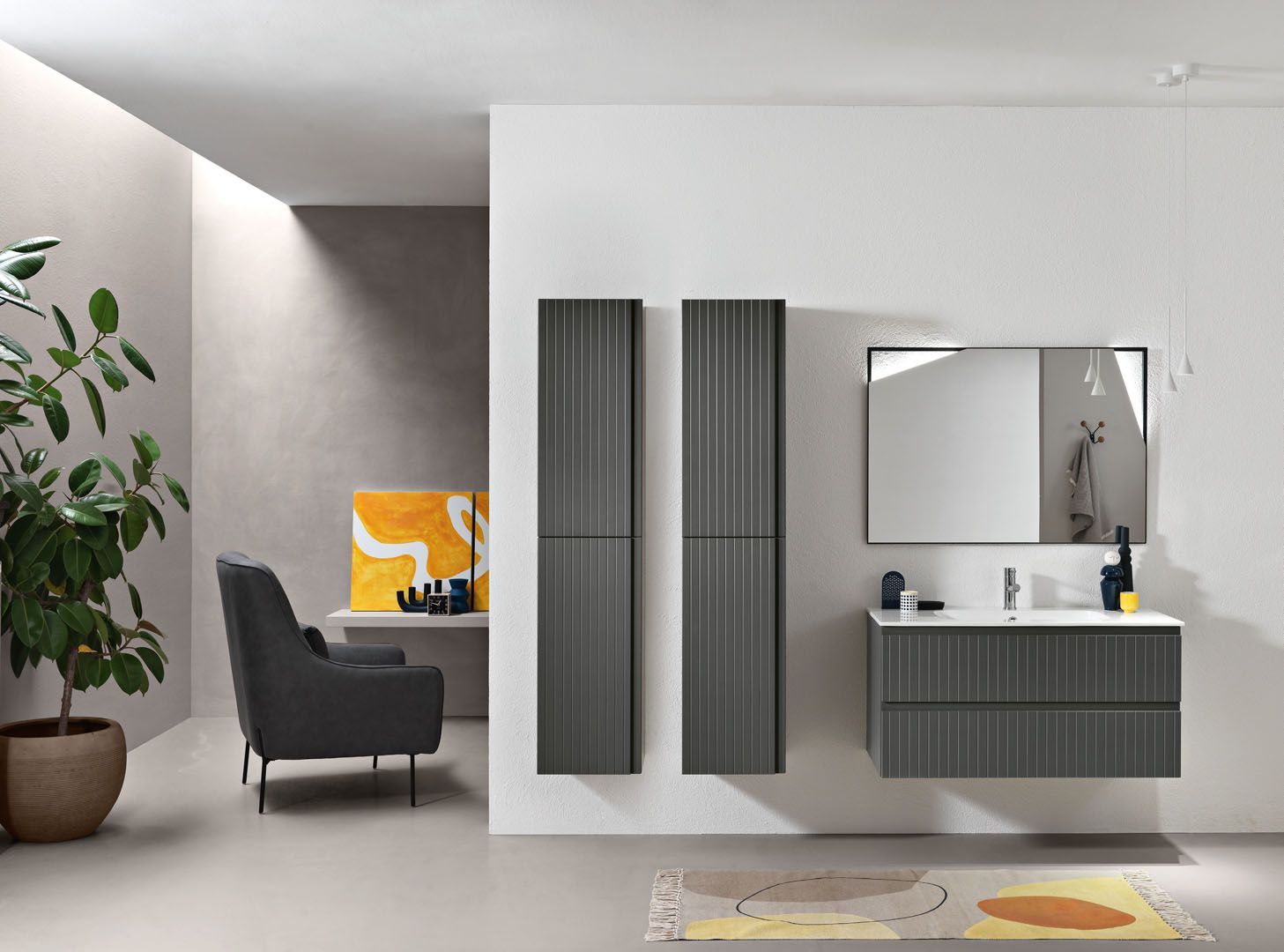 Bagno moderno con mobili grigi, specchio e due alti mobili contenitori.