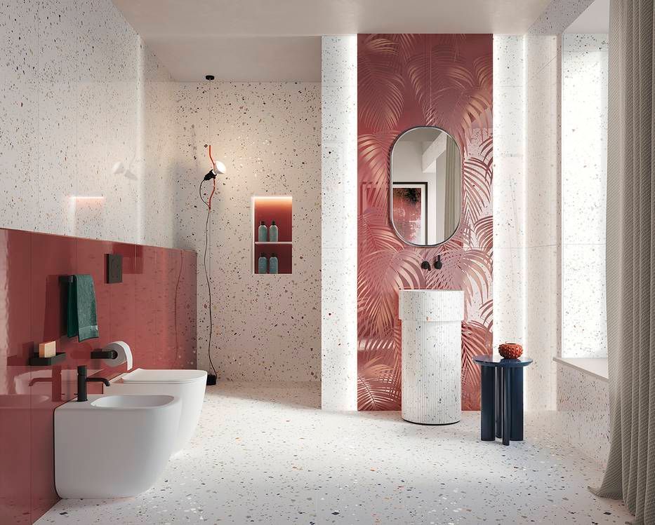 Bagno con pareti in terrazzo, dettagli rosa e una parete decorata con specchio e lavandino.