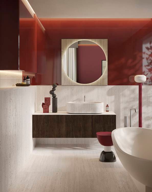 Moderno bagno rosso e crema con mobile lavabo sospeso, specchio rotondo e vasca da bagno scultorea.
