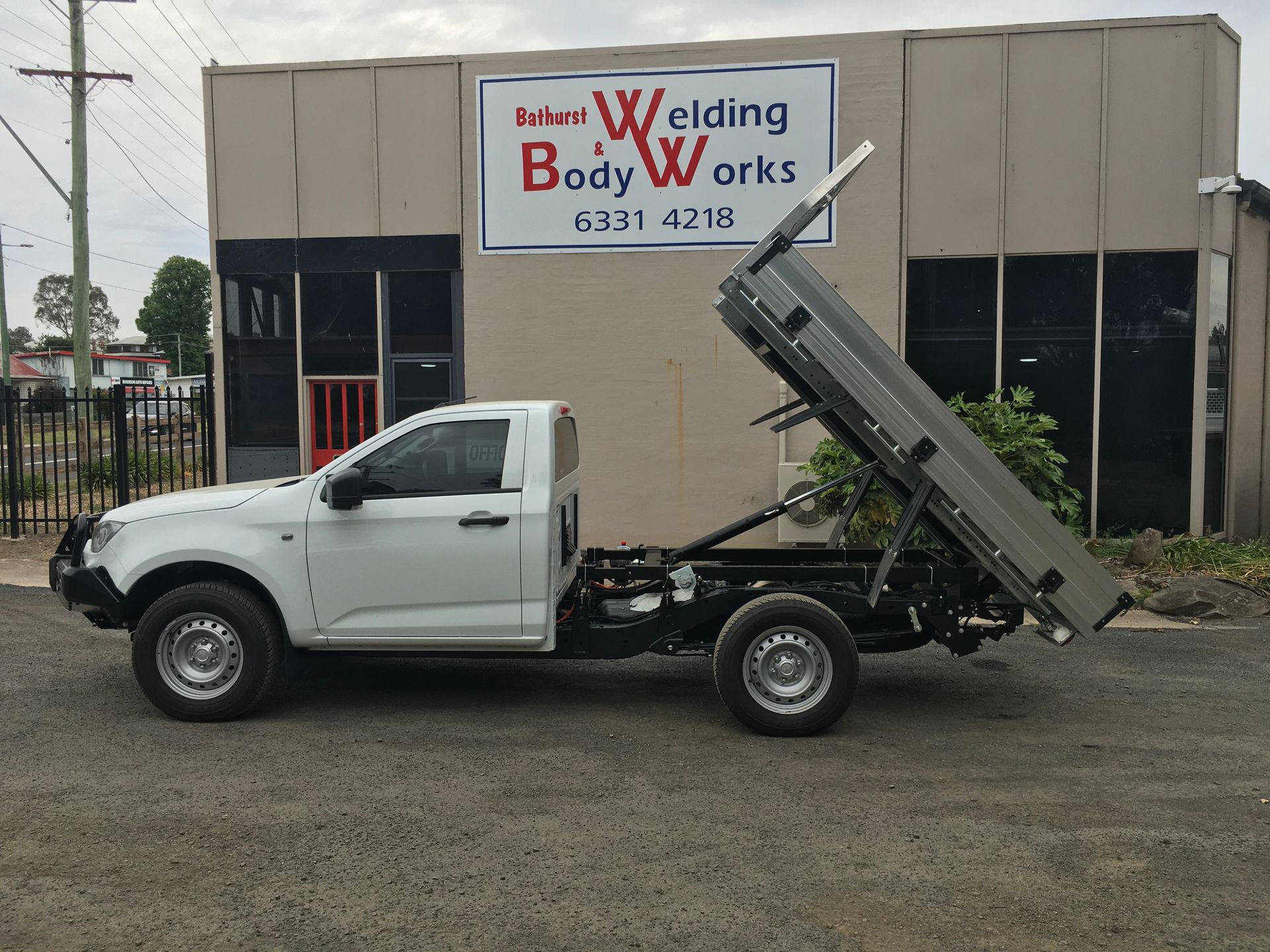 A Person Is Welding A Piece Of Metal On A Wooden Table — Bathurst Welding & Body Works In Canberra, ACT