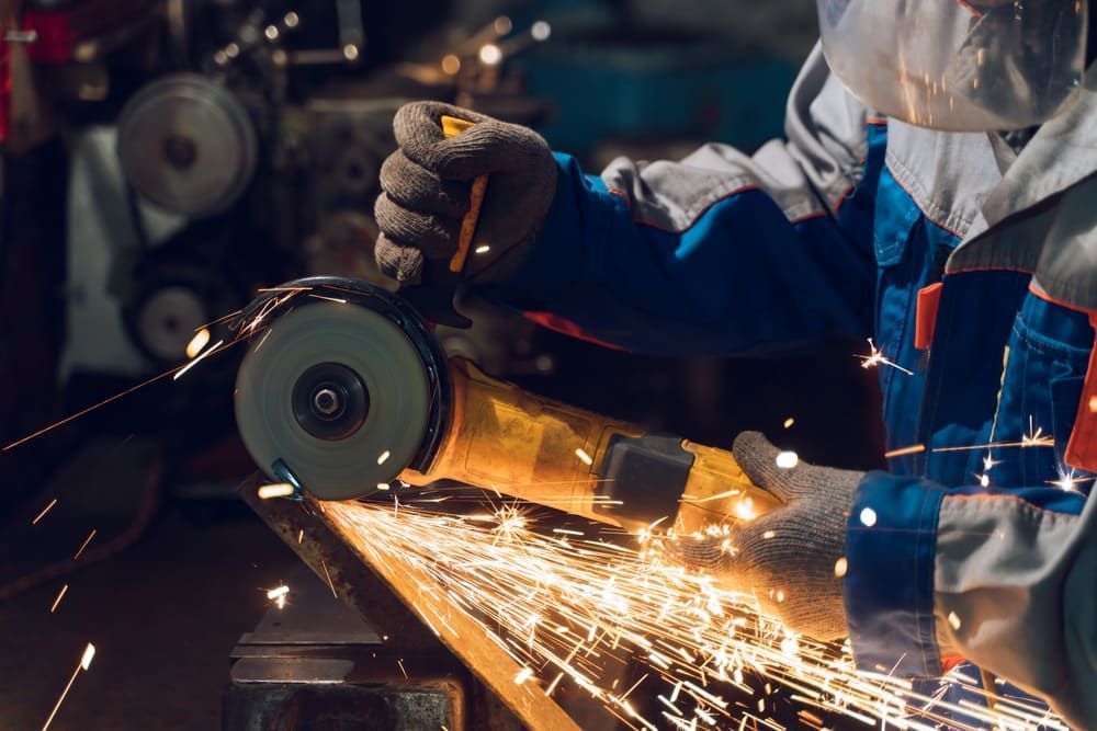 A Man Is Grinding A Piece Of Metal With A Grinder — Bathurst Welding & Body Works In Sydney, NSW