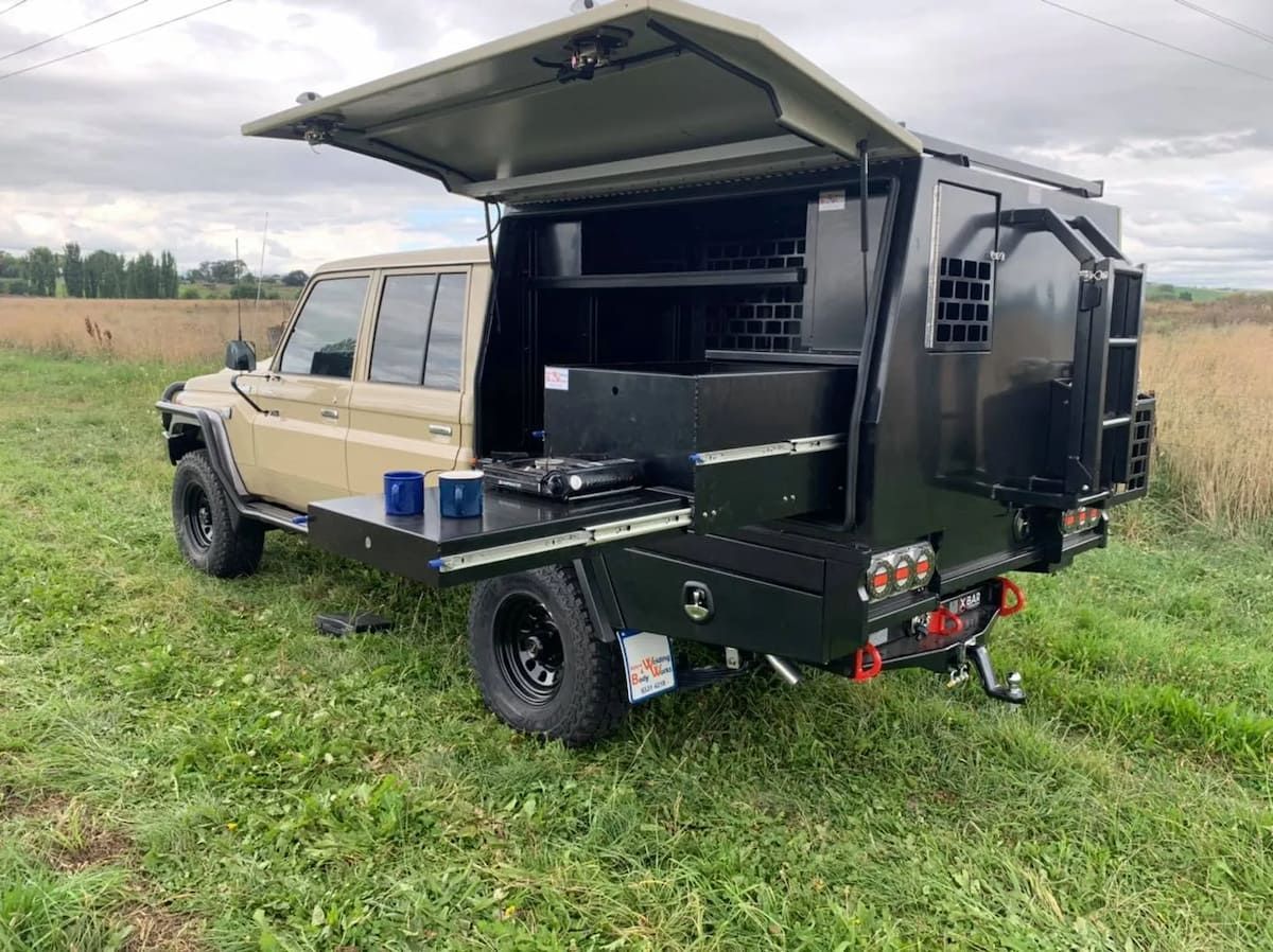 A Truck With A Trailer Attached To It Is Parked In A Grassy Field — Bathurst Welding & Body Works In Bathurst, NSW