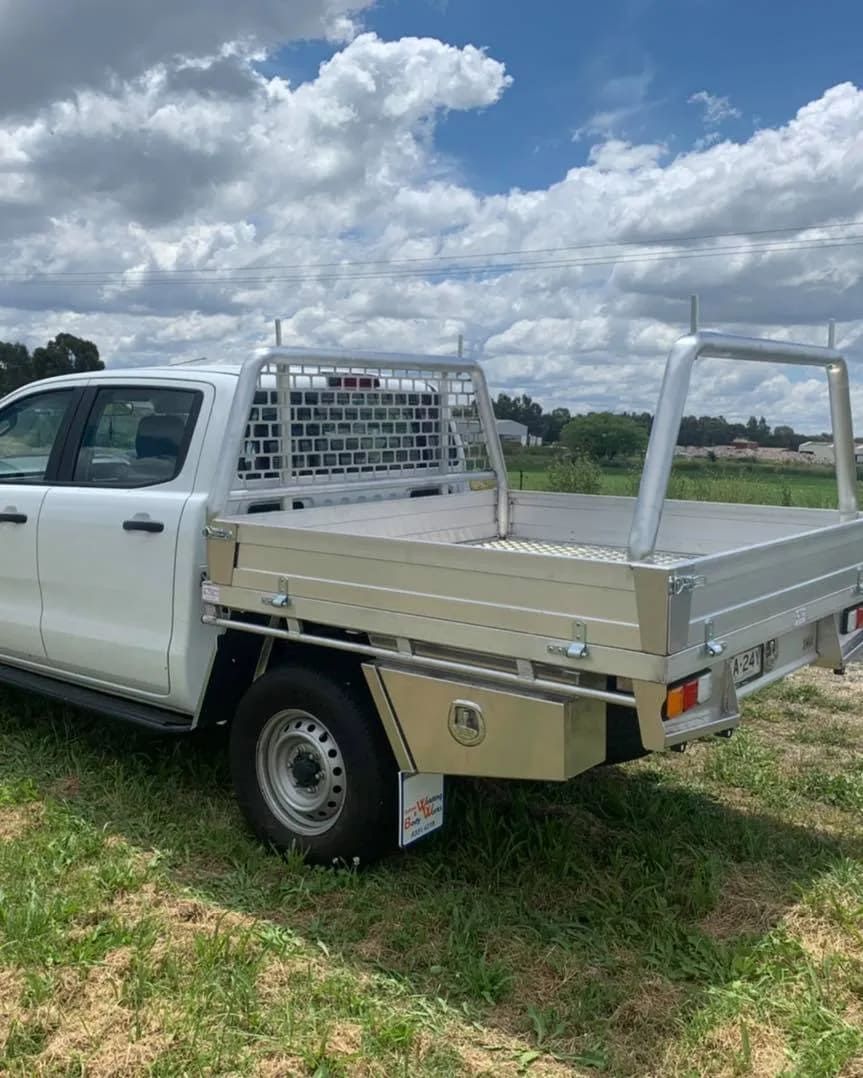 A White Truck With A Flat Bed Is Parked In A Grassy Field — Bathurst Welding & Body Works In Bathurst, NSW