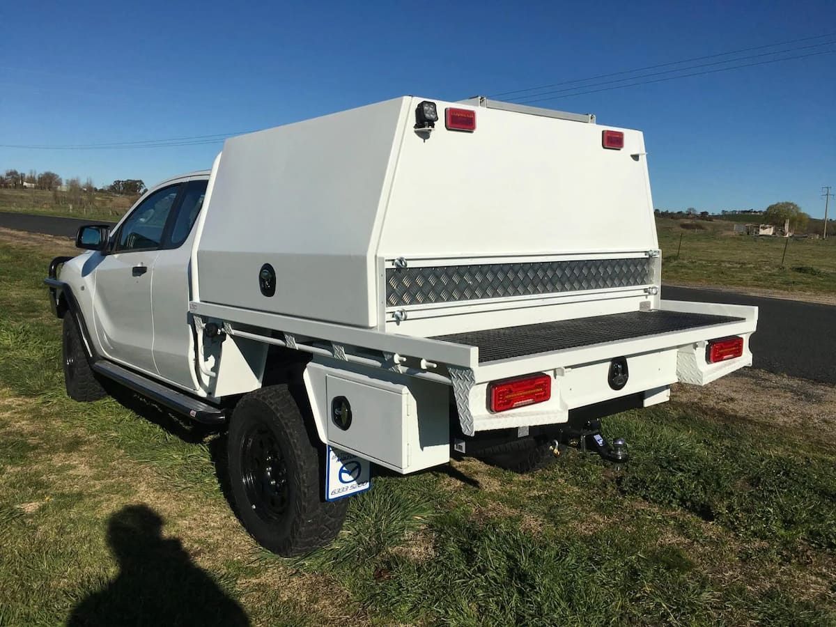 A White Truck With A Canopy And A Tray Is Parked In A Grassy Field — Bathurst Welding & Body Works In Bathurst, NSW