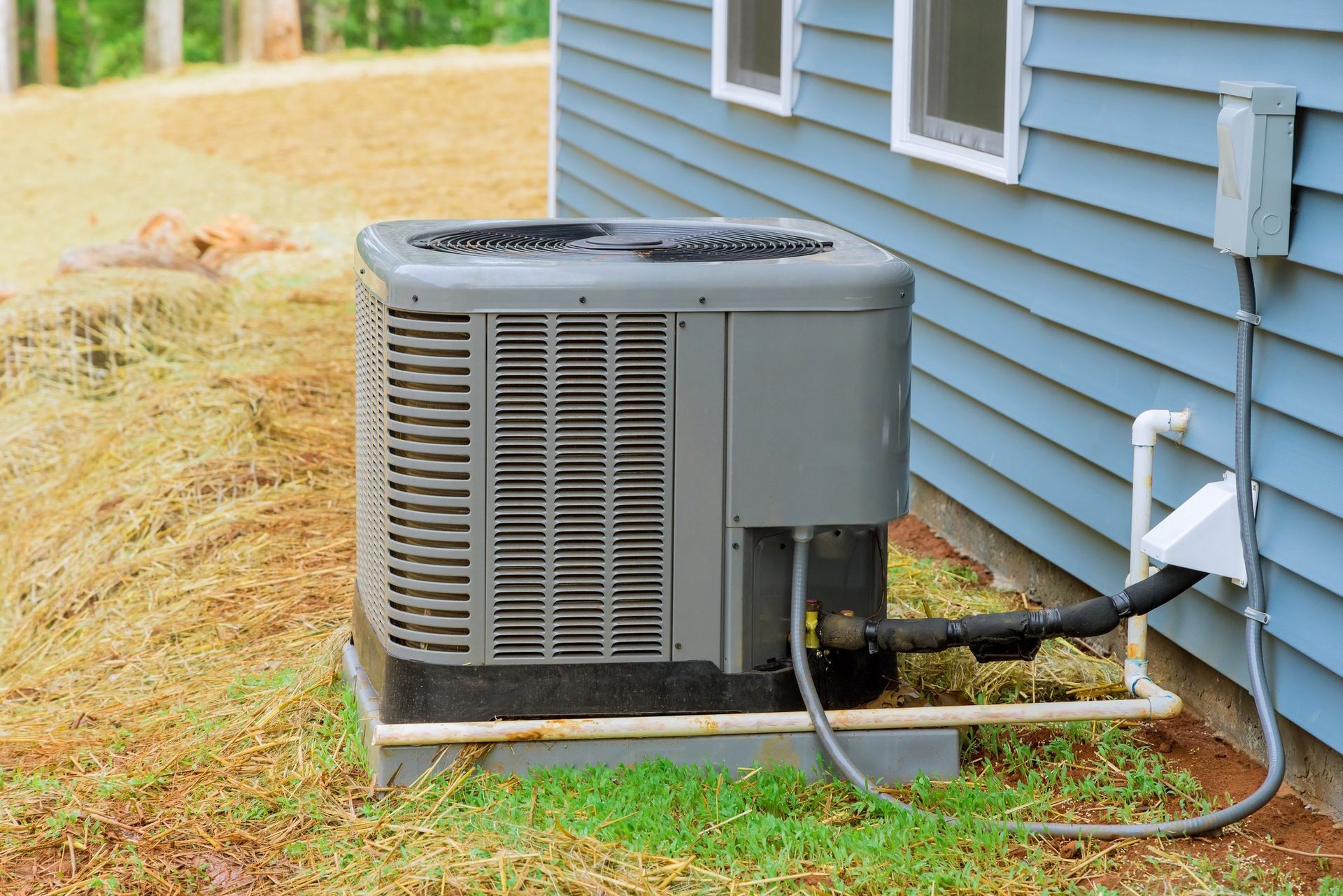 An air conditioner is sitting on the side of a house.