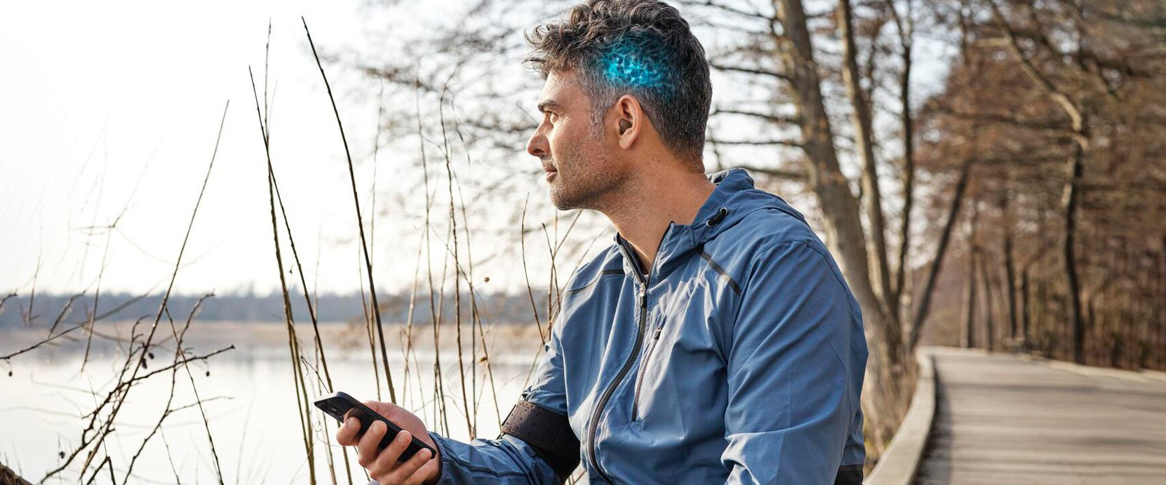 Un homme est assis sur un pont et regarde son téléphone portable.