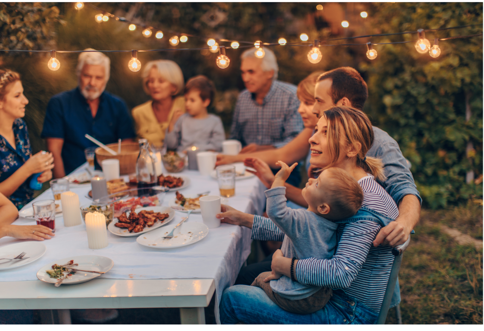 A large family is sitting around a table eating food.