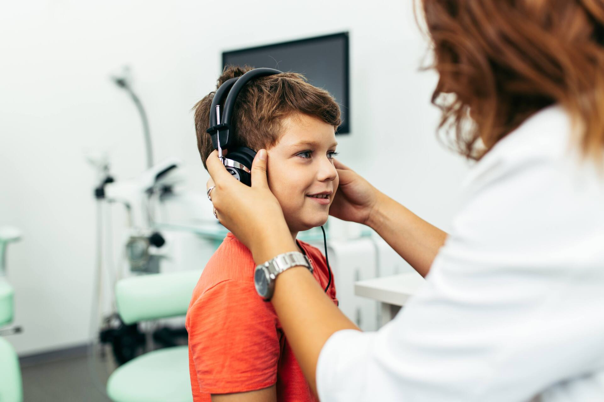 Une audiologiste met des écouteurs sur les oreilles d'un jeune garçon pour évaluer son audition