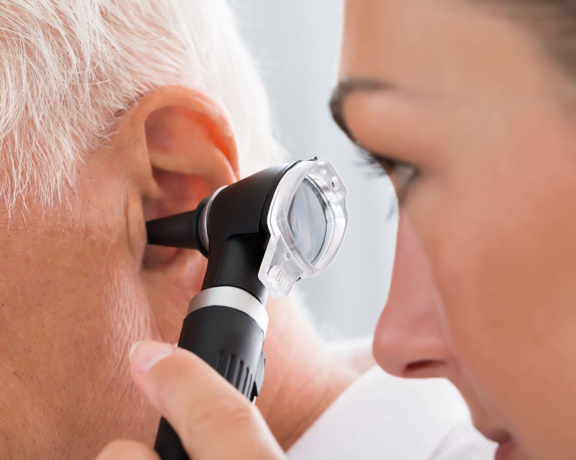 Audioprothésiste qui fait une otoscopie donc regarde dans l'oreille du patient avant le test dépistage auditif sans frais