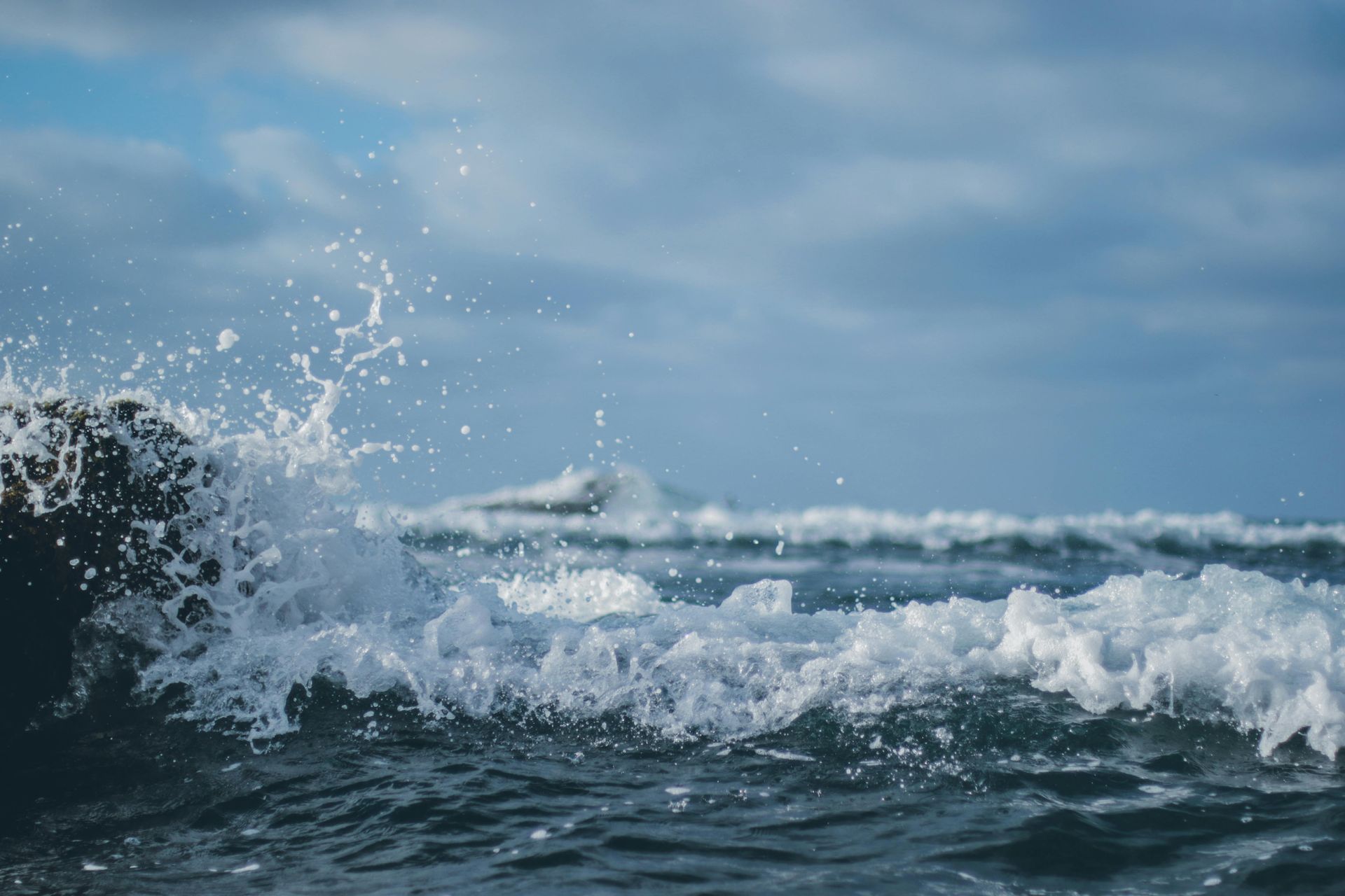A close up of a wave in the ocean on a cloudy day.