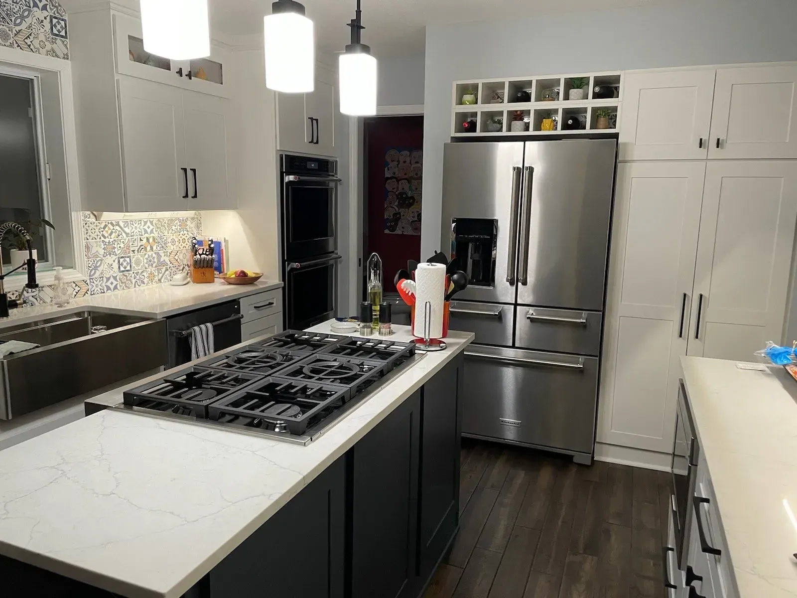Modern kitchen with stainless steel appliances, white cabinets, and a large island with a gas cooktop.