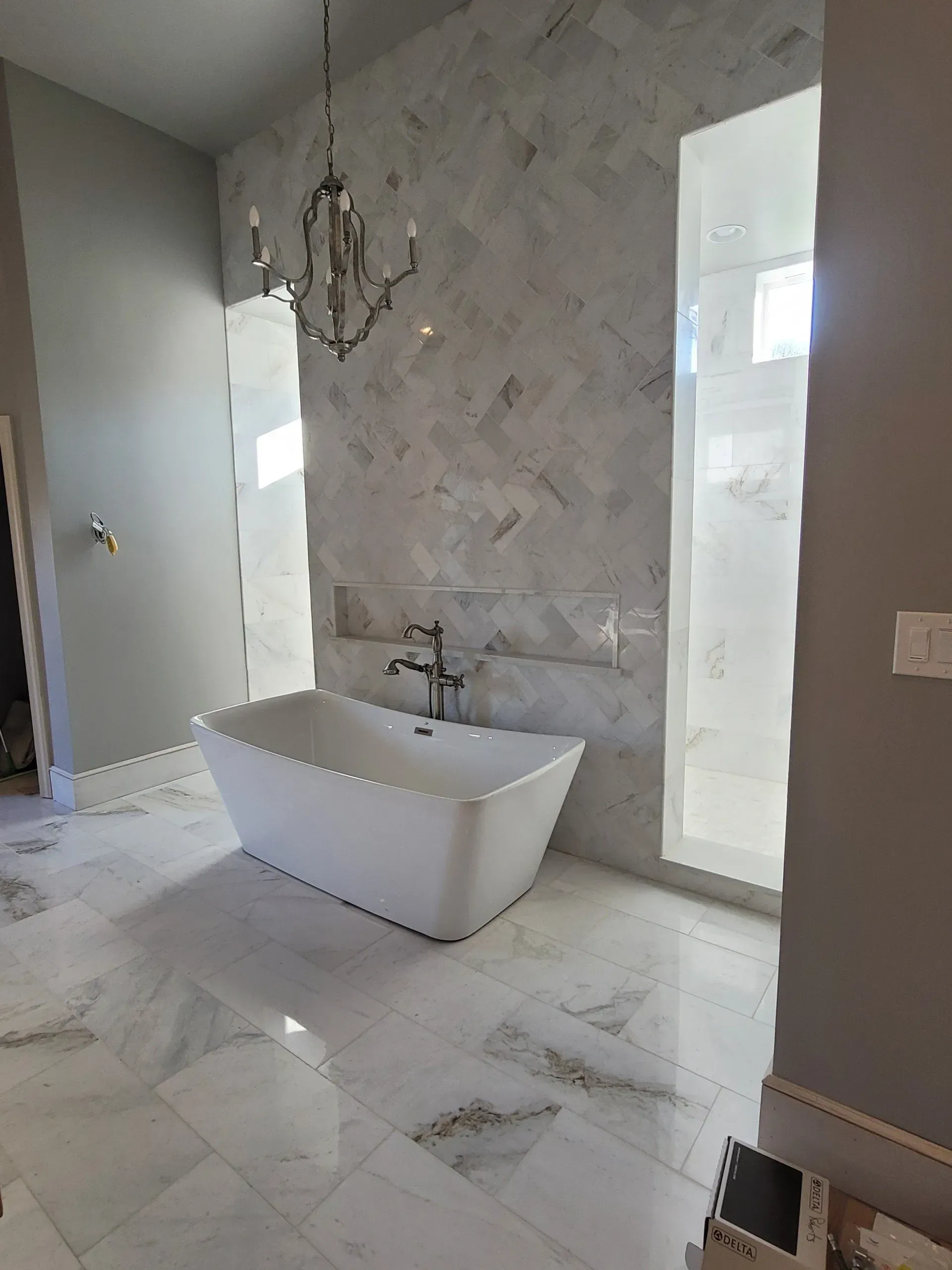 Modern bathroom with a freestanding tub, marble walls, and white tile floor