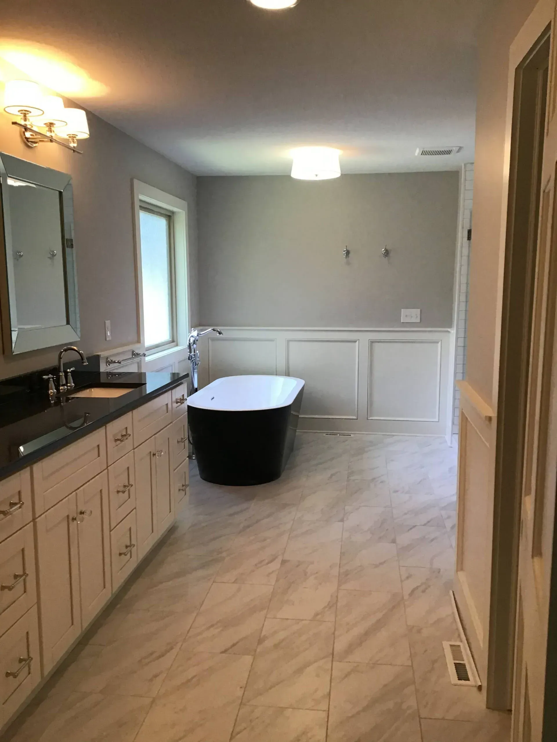 Bright bathroom with vanity, mirror, bathtub, and marble-pattern tile floor