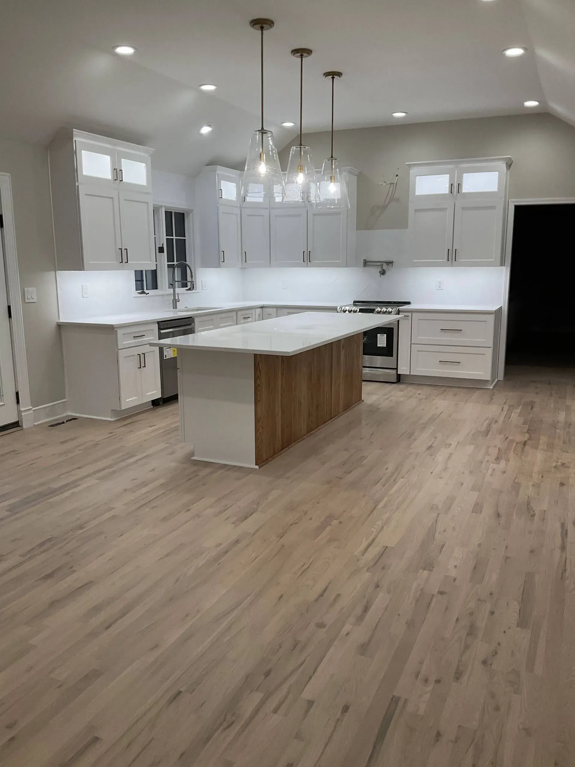 Bright modern kitchen with white cabinets, wood island, pendant lights, and light wood floors