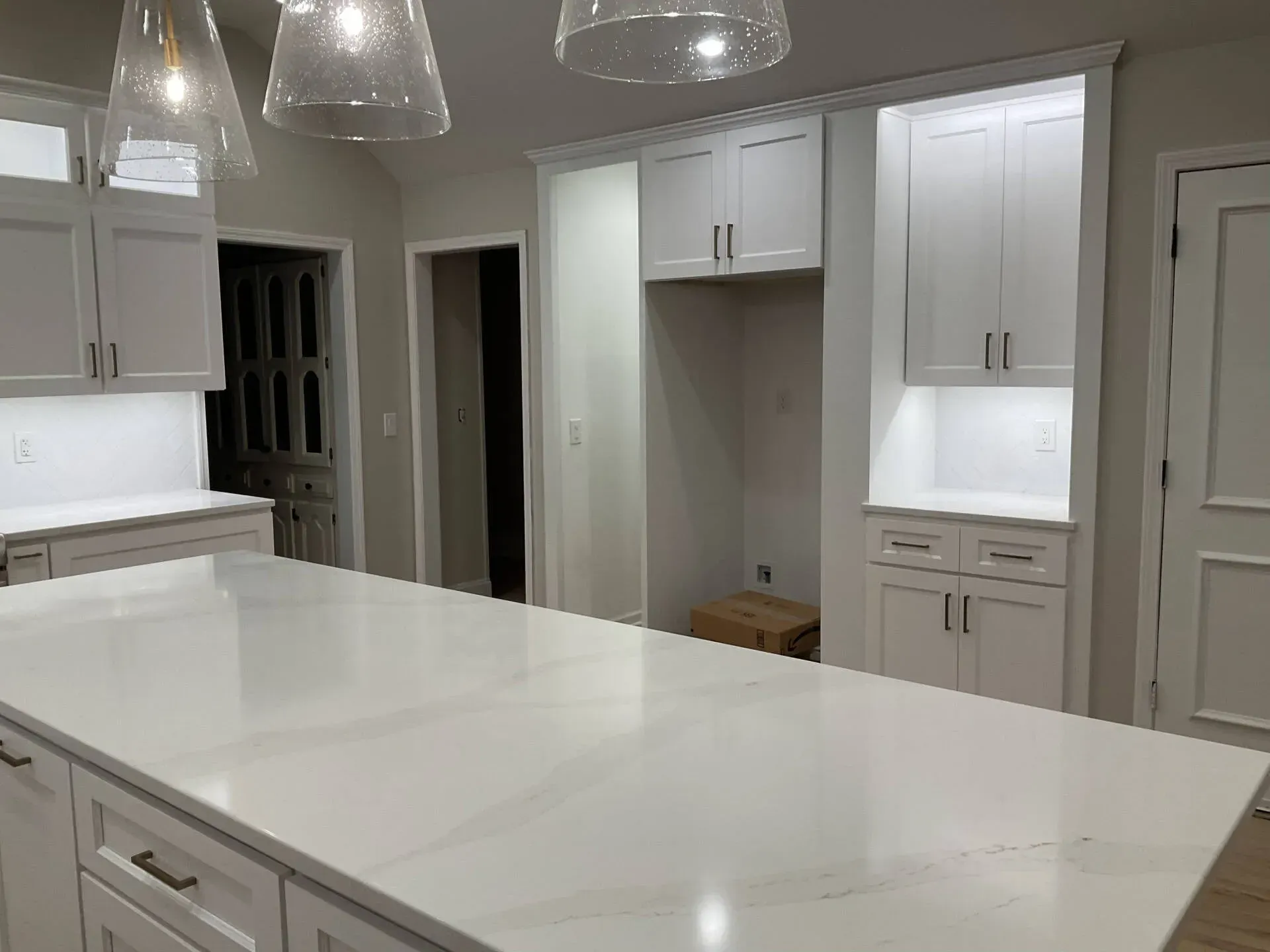 Bright white modern kitchen with island, pendant lights, and built-in cabinets