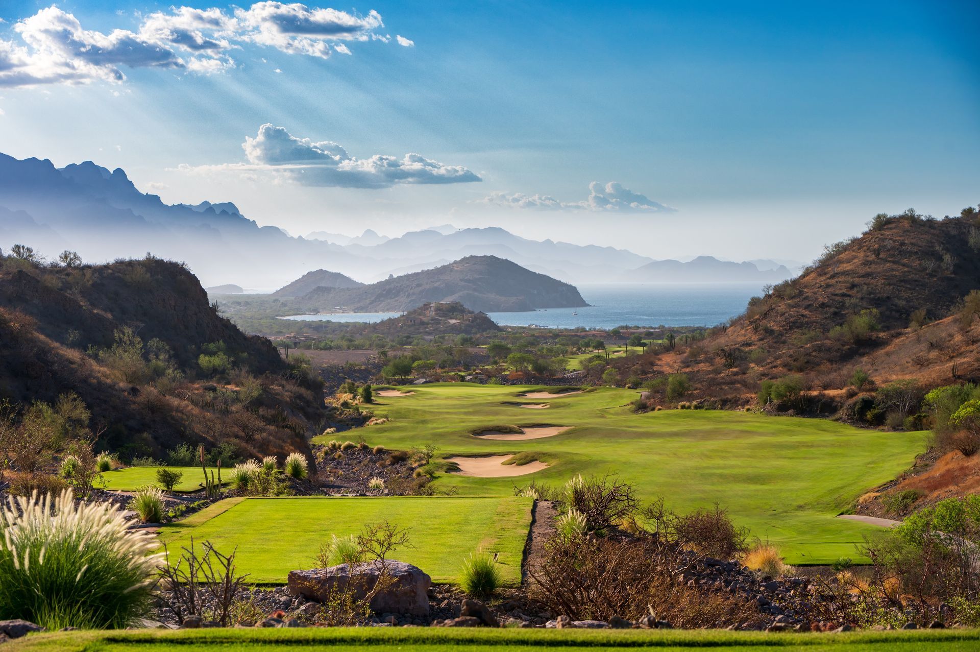 A view of a golf course with mountains in the background.