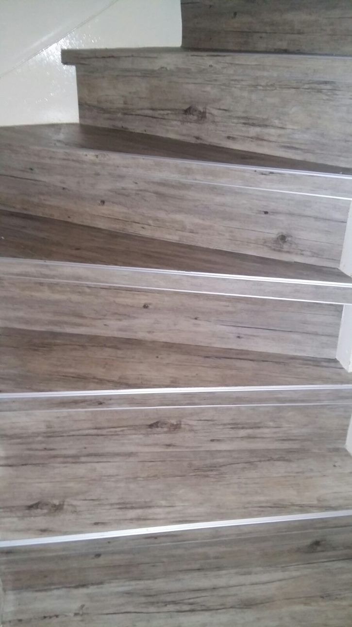 Een close-up van een houten trap met een metalen leuning.