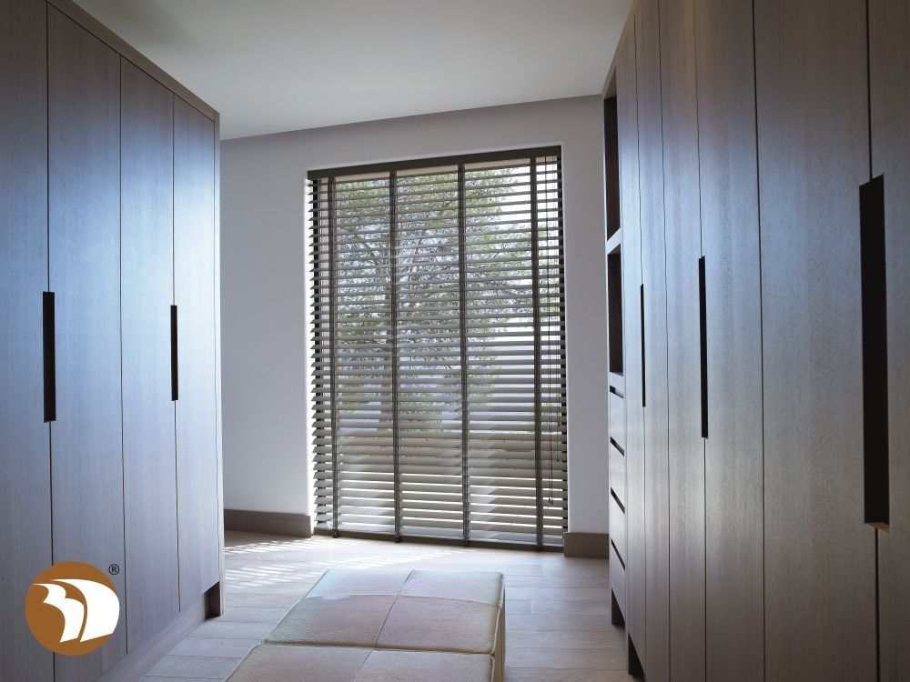 Een inloopkast met een groot raam en jaloezieën