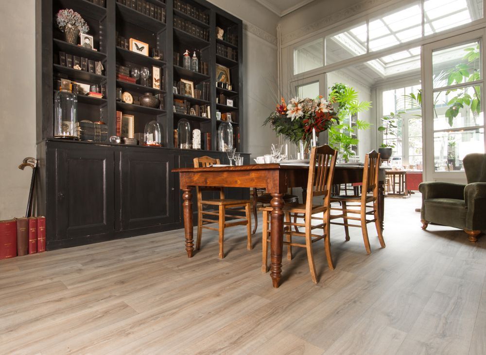 Een eetkamer met een tafel en stoelen en een boekenplank