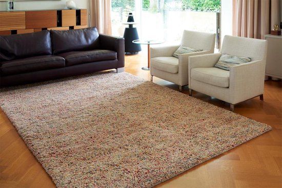 Een woonkamer met een bank, stoelen en een kleed.