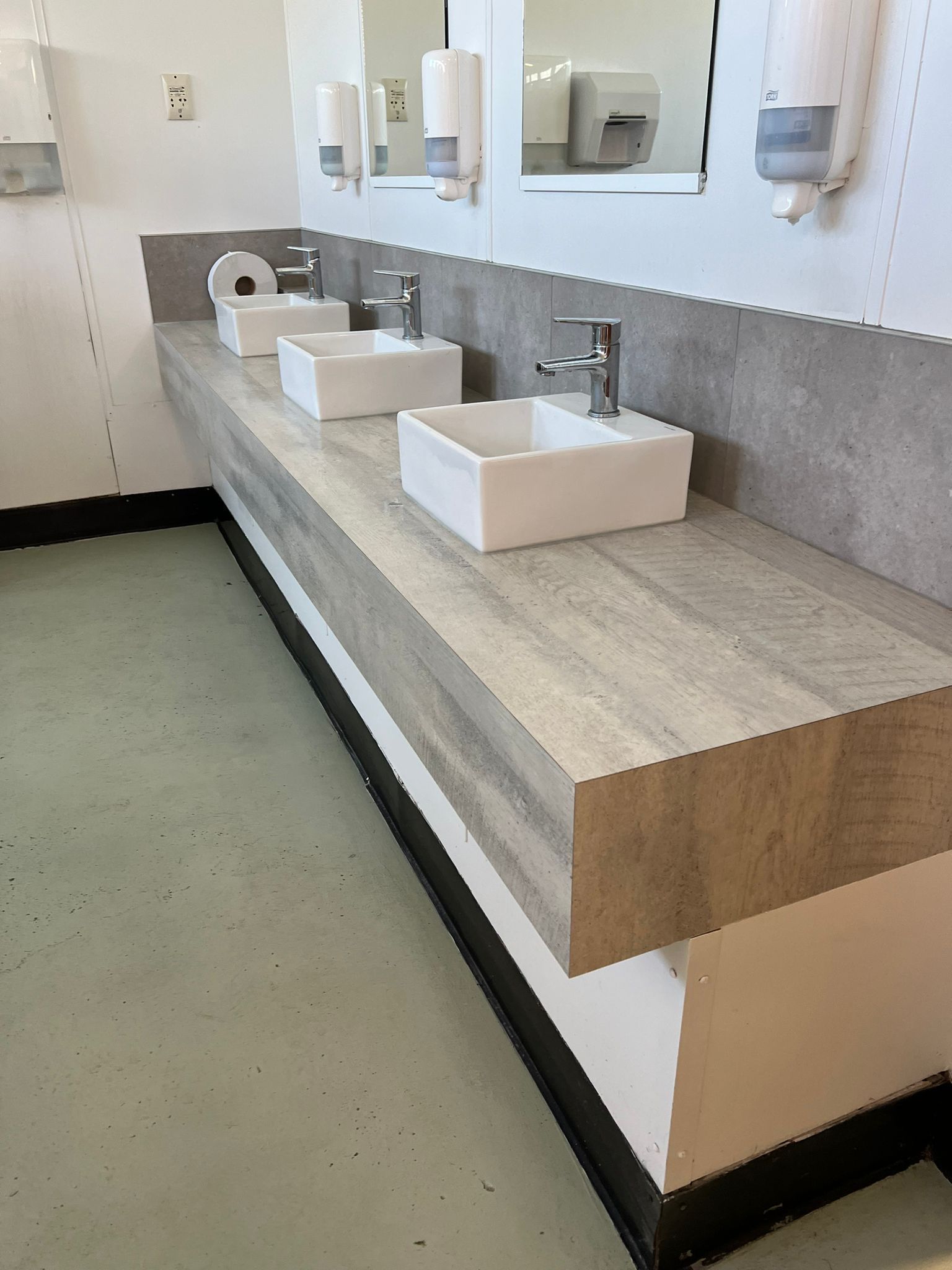 A bathroom with a row of sinks and mirrors.