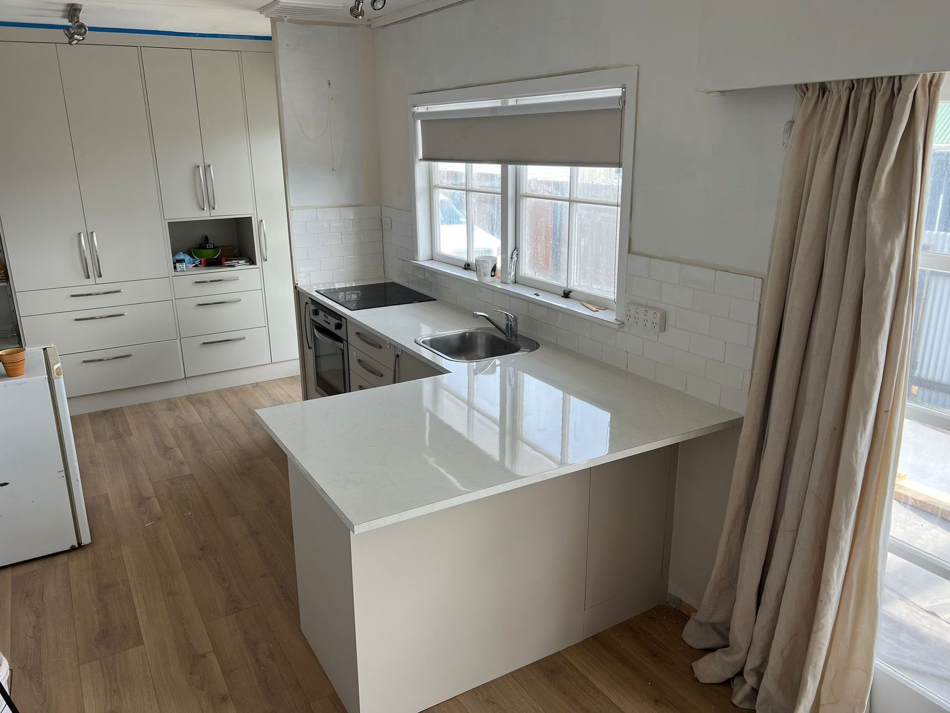 A kitchen with white cabinets , a sink , and a window.
