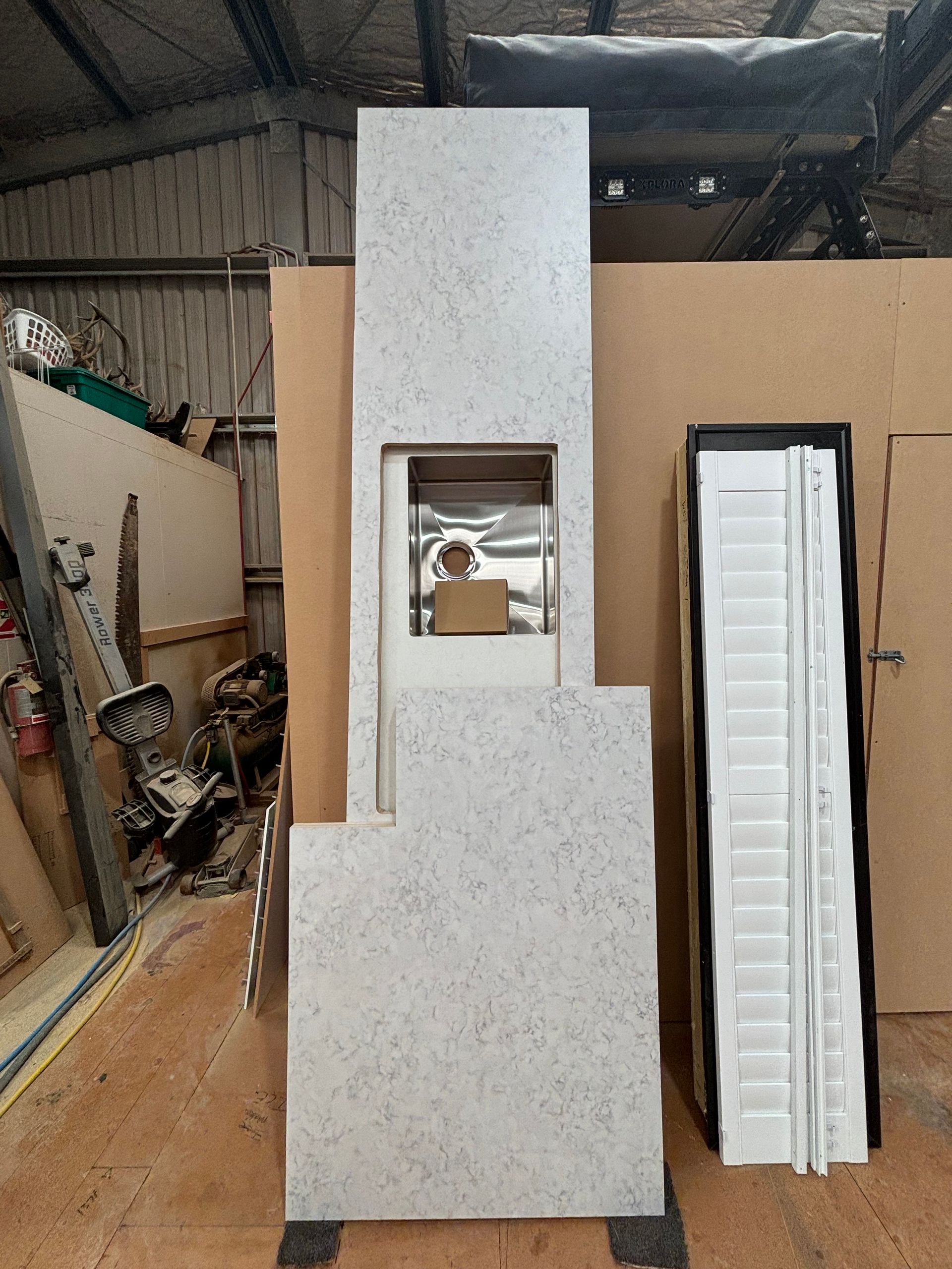 A white counter top is sitting in a warehouse next to a door.