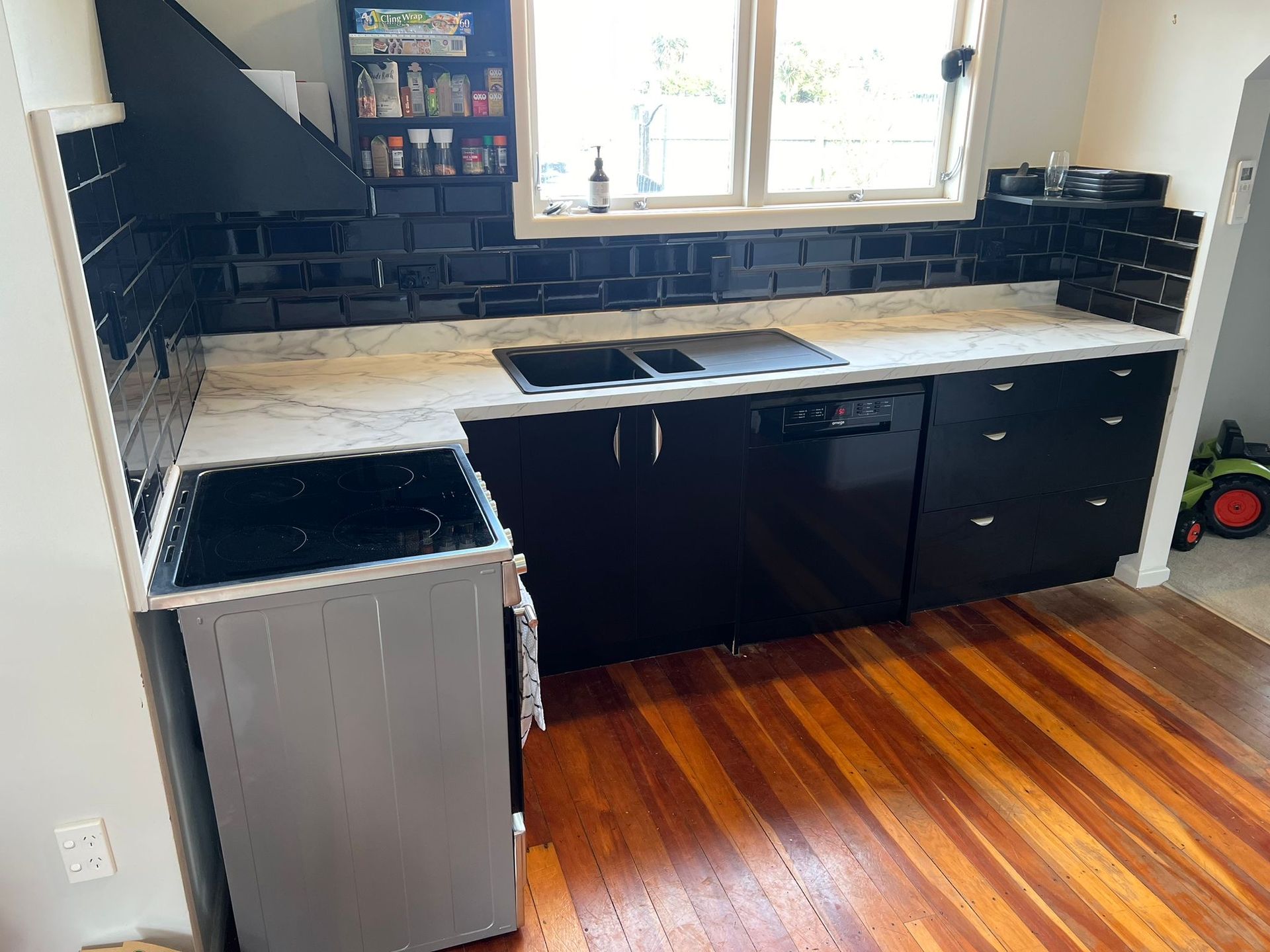 A kitchen with black cabinets and a wooden floor