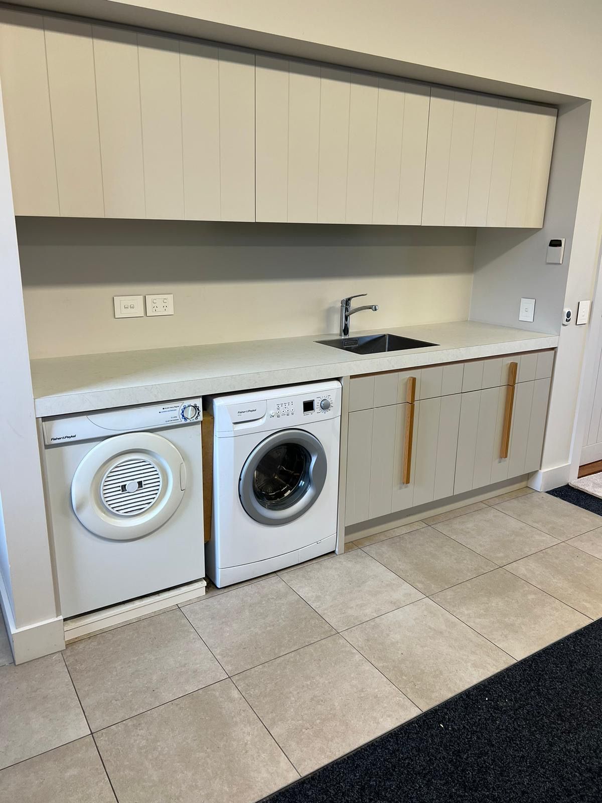 A laundry room with a washer and dryer and a sink.