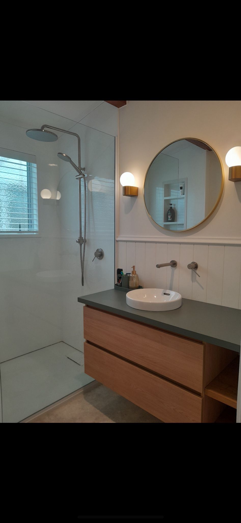 A bathroom with a sink , mirror and shower.