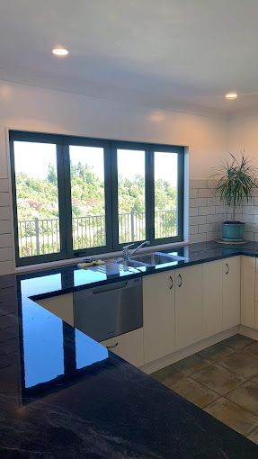 A kitchen with a sink , dishwasher , and large windows.