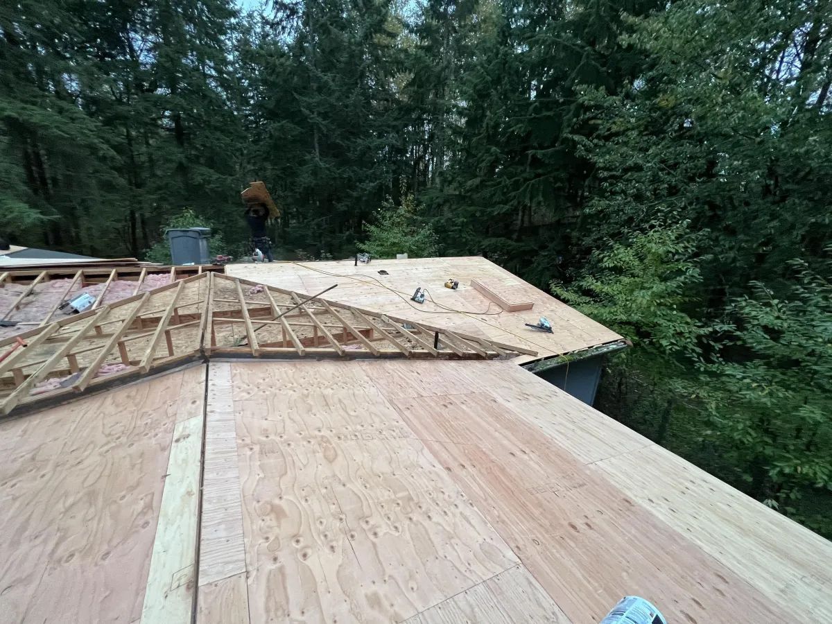 A man is standing on top of a wooden roof.