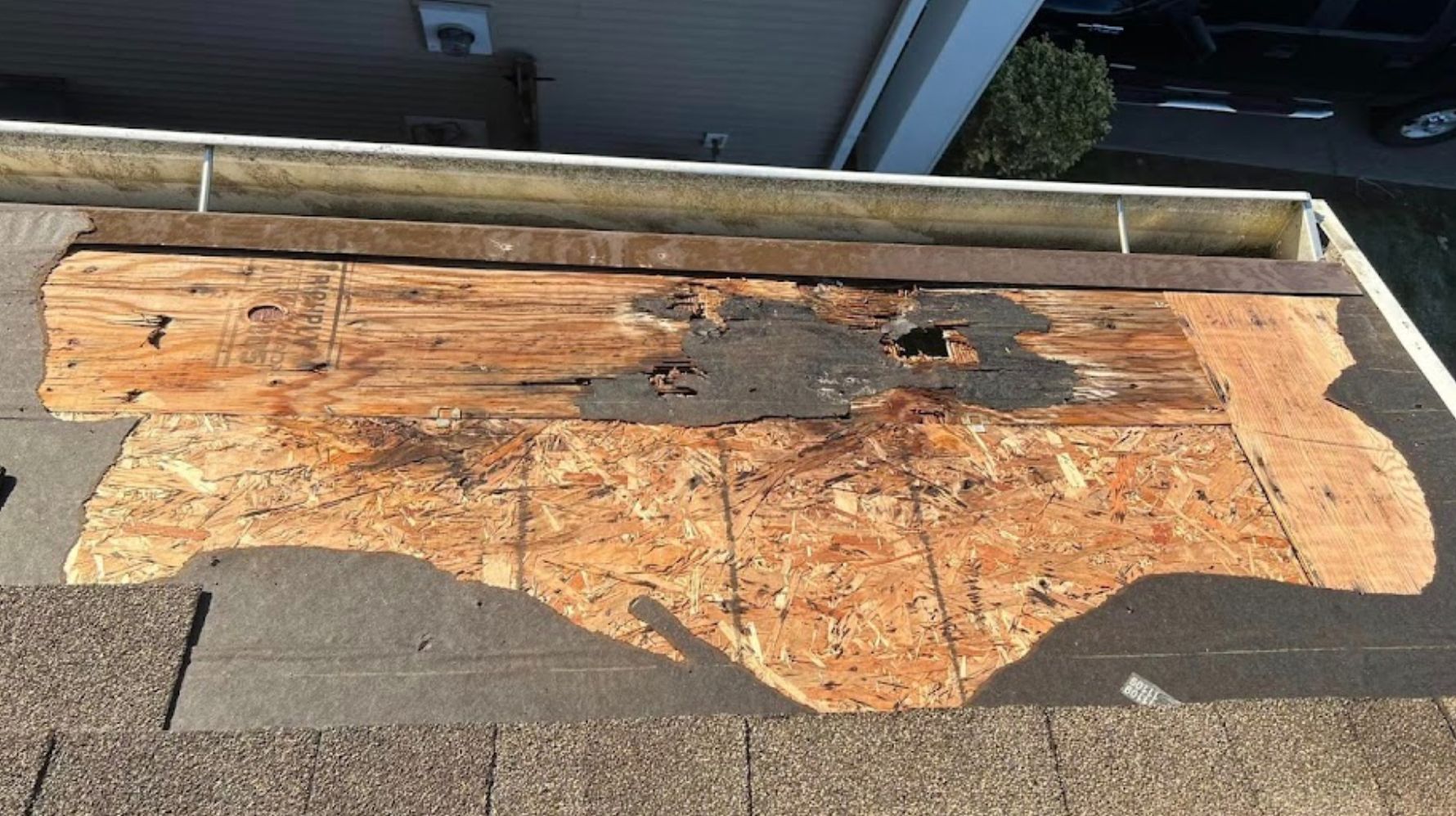 A piece of wood is sitting on top of a roof next to a gutter.