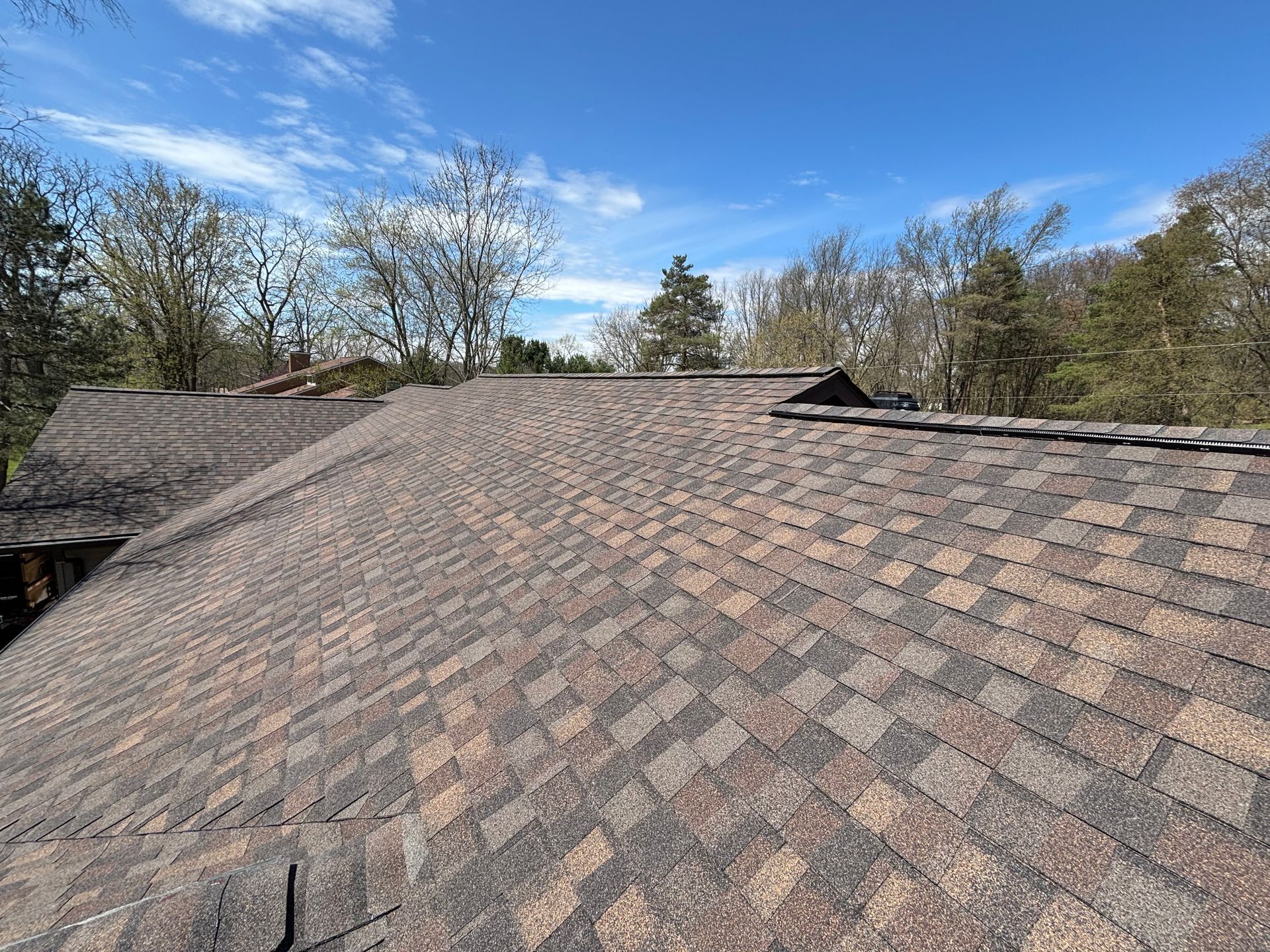 A roof under construction with rows of wooden battens, some partially covered with installed red rectangular roof tiles.