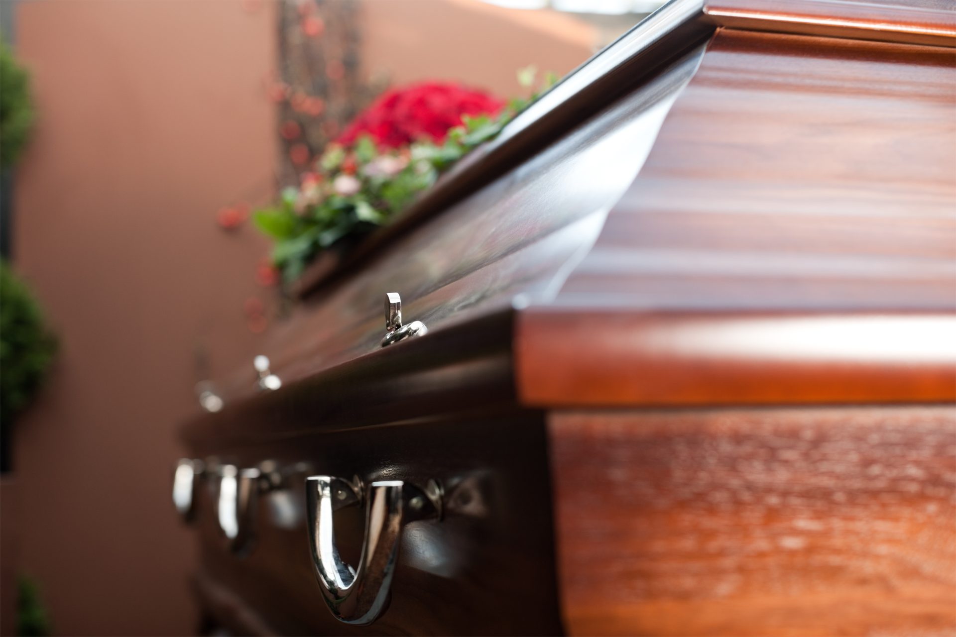 A man in a suit is sitting at a coffin at a funeral.