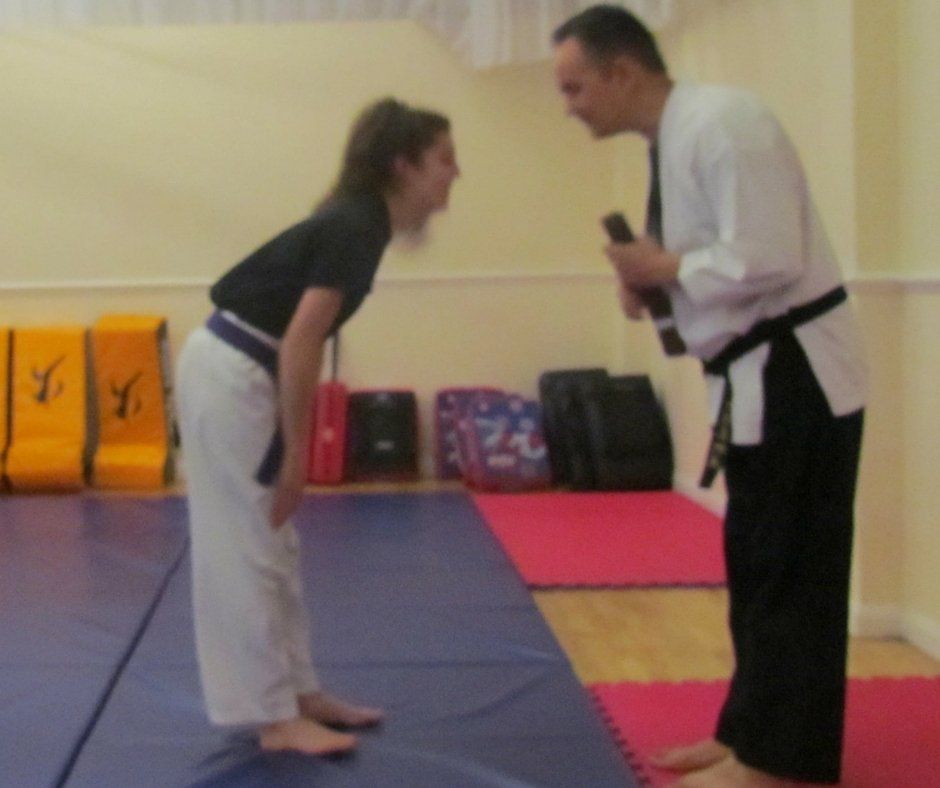 A man and a woman are standing on a mat in a gym