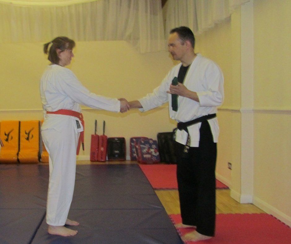 A man and a woman shake hands in a gym
