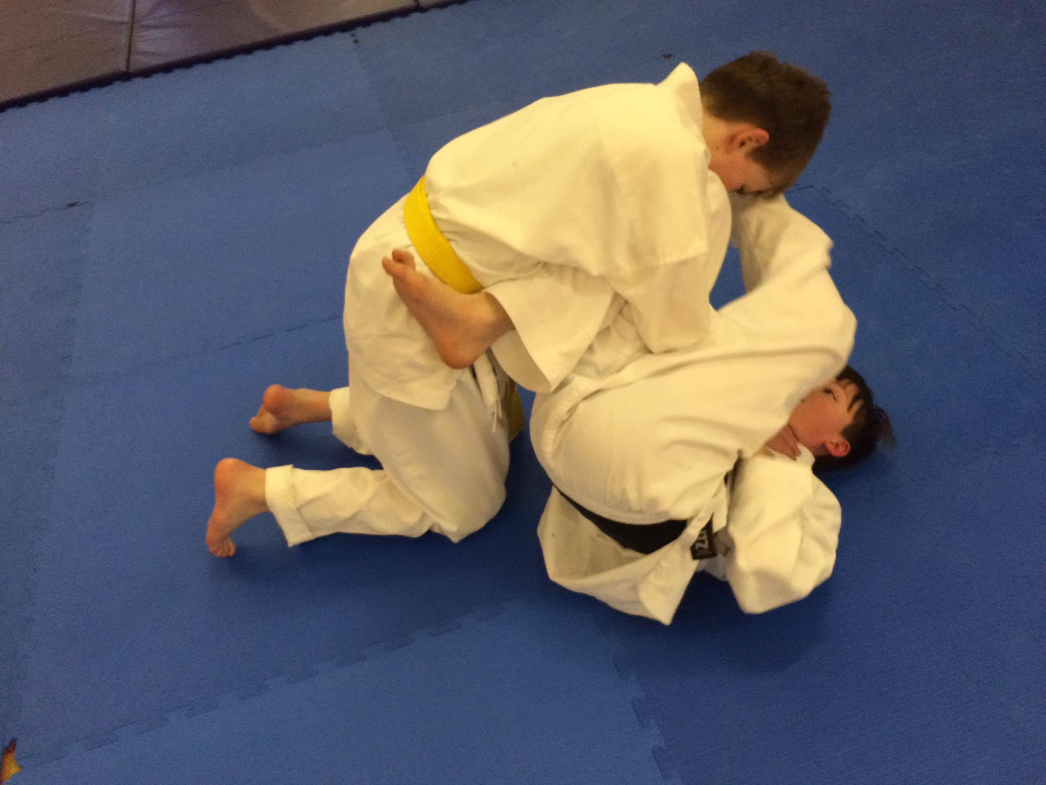Two boys are wrestling on a blue mat