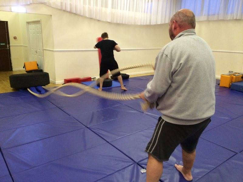 A man is holding a rope in a gym