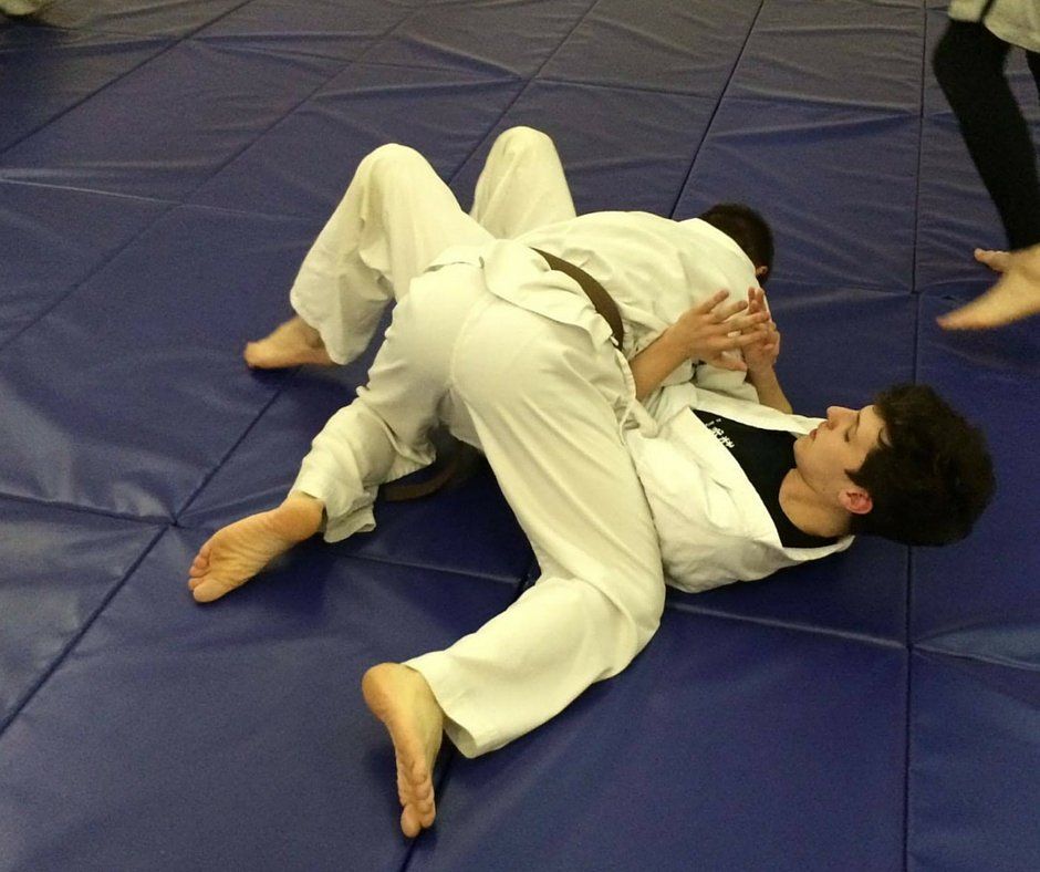 Two men are wrestling on a blue mat
