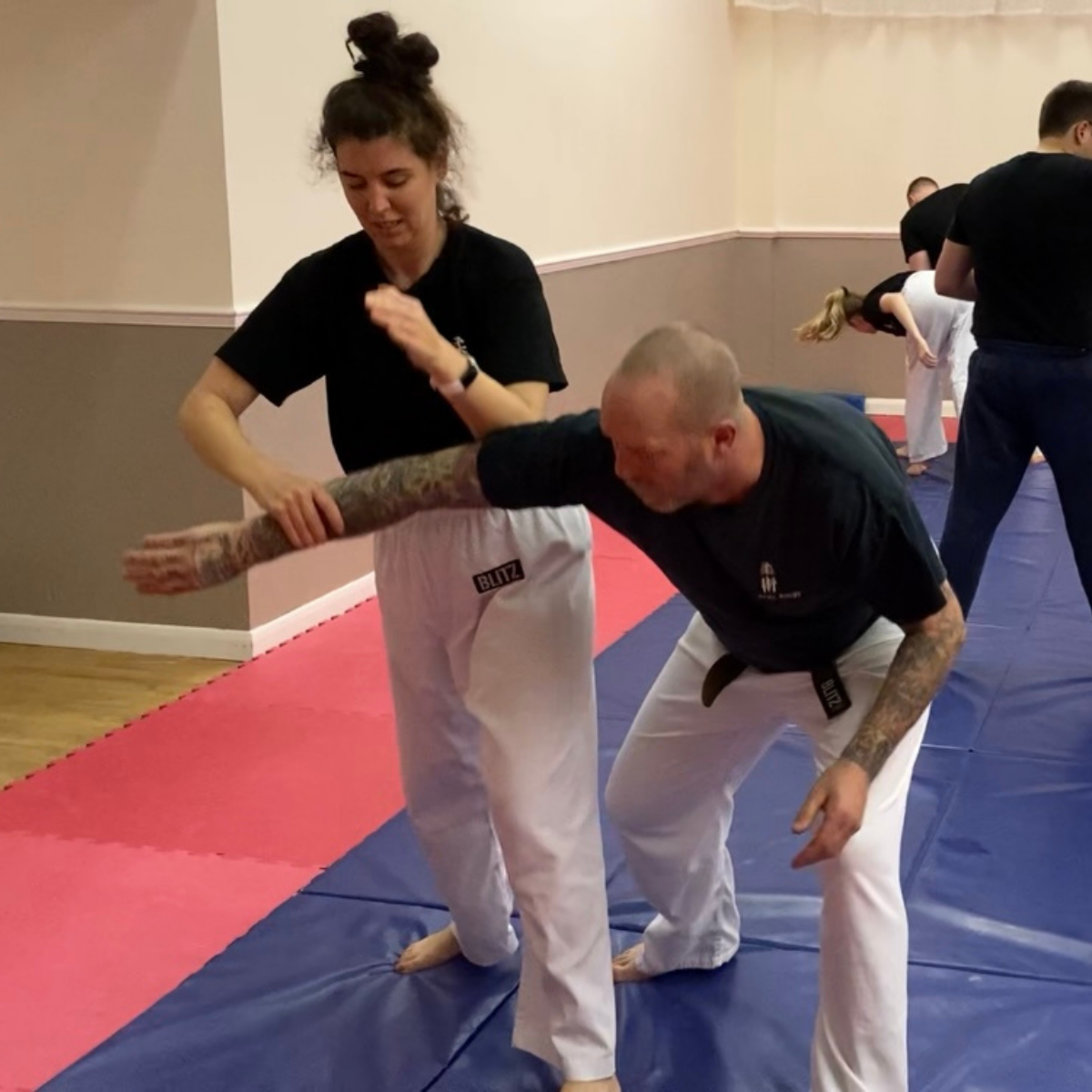 A man and a woman are practicing martial arts on a mat