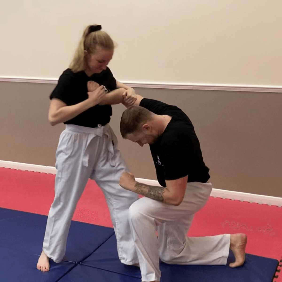 A man and a woman are practicing martial arts on a mat