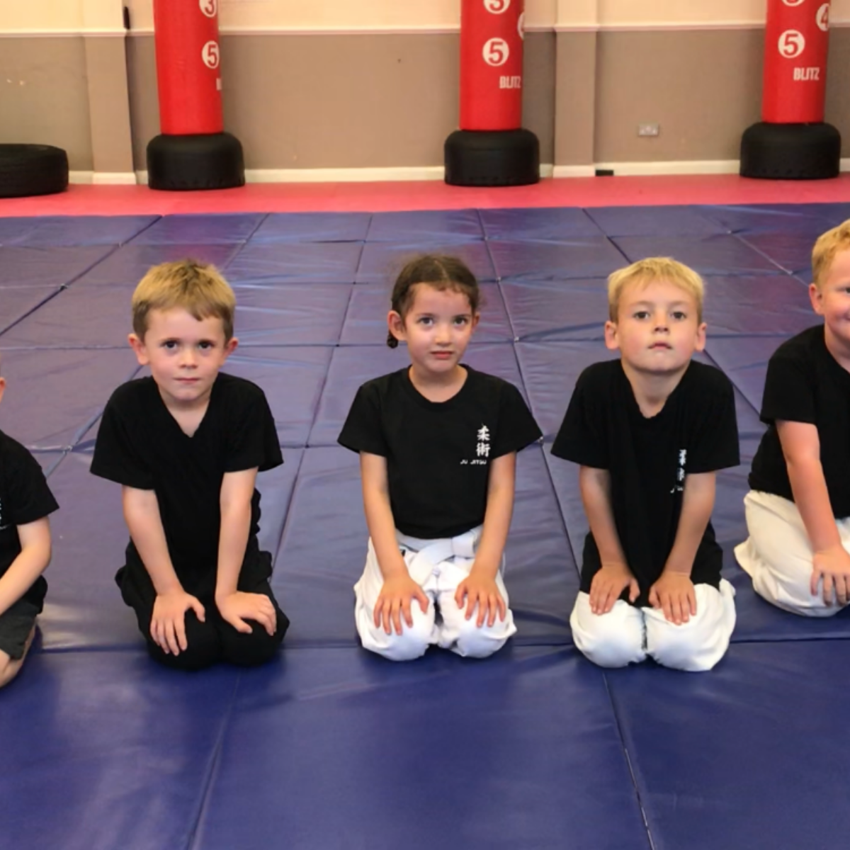 A group of young boys are sitting on a blue mat