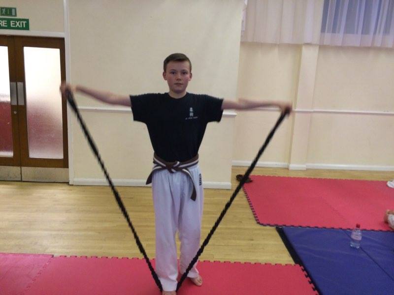 A man is holding a rubber band in front of a fire exit sign